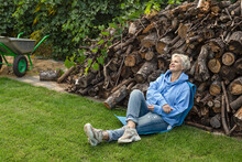 Serene Woman Resting At Woodpile In Backyard
