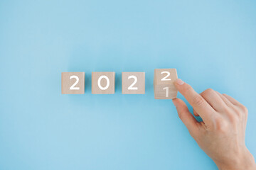 Hand flip wooden cube with the number 2021 to number 2022 on white background. Merry Christmas and happy new year concept