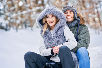 Wall Mural - Couple having fun with sledge on snow in winter