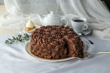 Wall Mural - homemade glazed cake and slice decorated with chocolate cream roses and cup of tea on the table