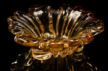 Vase Of Orange Glass On A Black Background. At The Bottom Of The Image Is A Reflection Of The Vase.