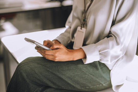 Curly-haired woman sitting on the table with a phone in hands