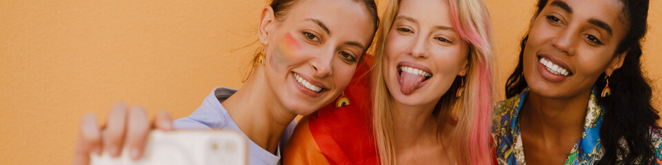 Wall Mural - Multiracial women with rainbow flag taking selfie photo on cellp