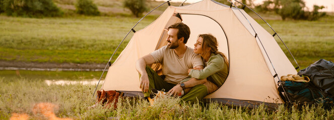 white couple hugging and sitting in tent during camping together