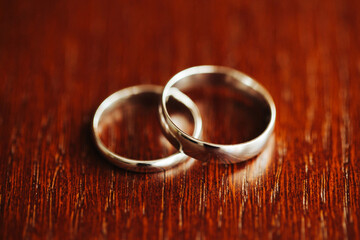 Wall Mural - White gold wedding rings. Closeup wedding jewelry. Metal rings on wooden table. Getting ready to get married. Symbol of being together.