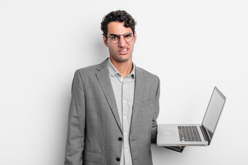 Wall Mural - hispanic handsome man feeling puzzled and confused. business and laptop concept