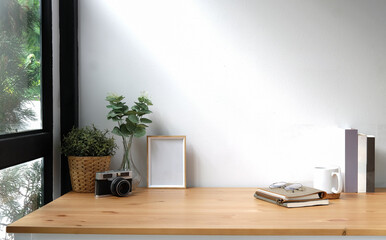 Aufkleber - Creative workspace with blank poster frame, camera, coffee cup and houseplant on wood table..