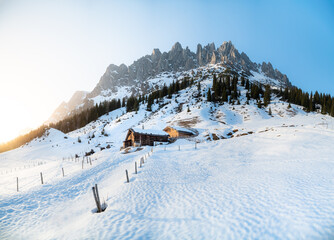 Wall Mural - Winter wonderland mountain scenery in the Alps with traditional mountain huts at sunset