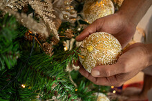 Hands Holding Decoration Balls On The Christmas Tree.