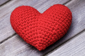 Sticker - a beautiful knitted heart lies on a gray wood textured background. Love concept