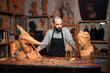 © ADDICTIVE STOCK - Serious carpenter at table with carved sculptures