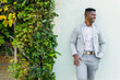 © ADDICTIVE STOCK - Smiling black man standing leaning on white wall