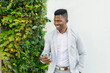 © ADDICTIVE STOCK - Smiling black man in stylish clothes browsing smartphone