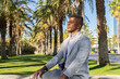 © ADDICTIVE STOCK - Relaxed black businessman sitting in tropical park