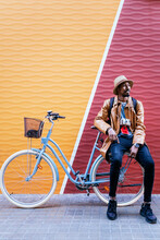 Black Man On Bicycle Near Colorful Wall