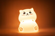 © Марина Демешко - The baby cute kitten-shaped light night lamp with eyes and ears on the bedside table in the dark