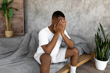 Black Man Suffering From Headache Or Migraine In Bed