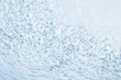 Blue seething water background with flying drops, bubbles and circles on the surface. Modern concept for perfect design