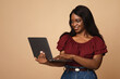 Smiling black lady working online, using laptop, studio shot