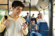 © Prostock-studio - Haapy Asian guy using cell phone in bus