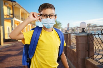 Poster - Young child in mask and a uniform with a backpack outdoors. Back to school.