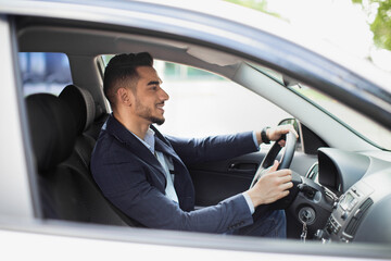 Wall Mural - Cheerful middle eastern manager driving car, side view