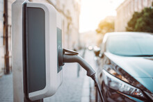 Power Supply For Electric Car Charging. Electric Car Charging Station On Urban Europe Street With Blurred Nature Background.