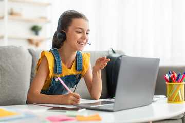 Poster - Smiling girl in headset using laptop, talking during videocall