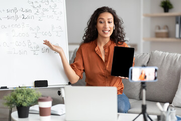 Wall Mural - Female teacher explaining math online showing tablet with empty screen