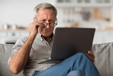 Fototapeta  - Older Male Squinting Eyes Using Laptop Wearing Eyeglasses At Home
