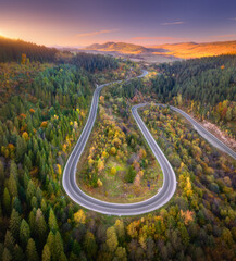 Wall Mural - aerial view of mountain road in forest at sunset in autumn. top view from drone of road in woods. be