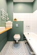 Minimalistic elegant design of bathroom in wormwood green color, installation, white bath. Wall paint for wet room using