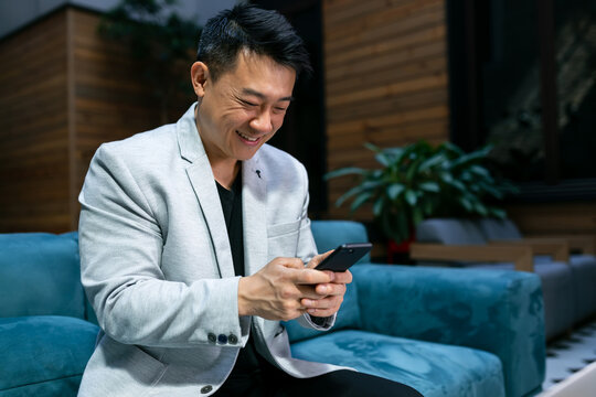 Portrait of a young confident male businessman dressed in a luxurious suit talking on the phone during work break, smart man using his mobile phone while preparing for a business meeting in the office