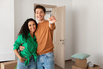 Happy couple showing keys from flat on moving day