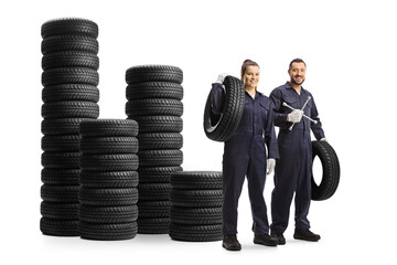 Wall Mural - Male and female auto mechanic workers with a lug wrench tool standing next to a pile od tires