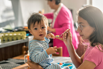 Latin baby boy eating breakfast sitting down at the kitchen table