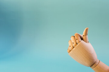 A wooden android hand with a raised thumb on a blue background. The conceptual gesture is all in order