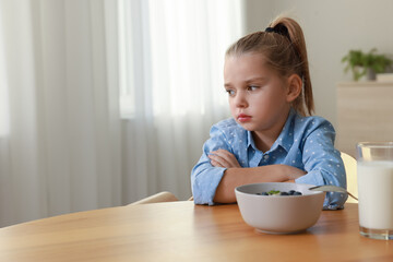 Poster - Cute little girl refusing to eat her breakfast at home, space for text