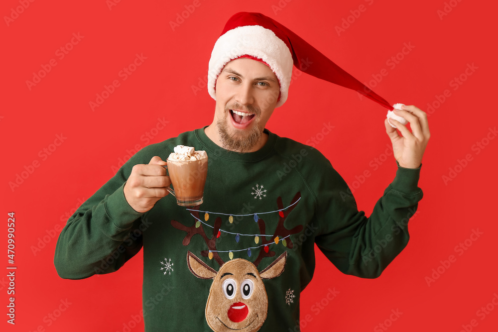 Handsome man with cup of hot cocoa on color background