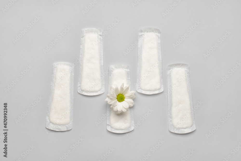 Menstrual pad and chamomile flower on light background