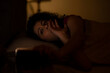 © IndiaPix - Woman watching smartphone with sleepy eyes at night while lying on bed