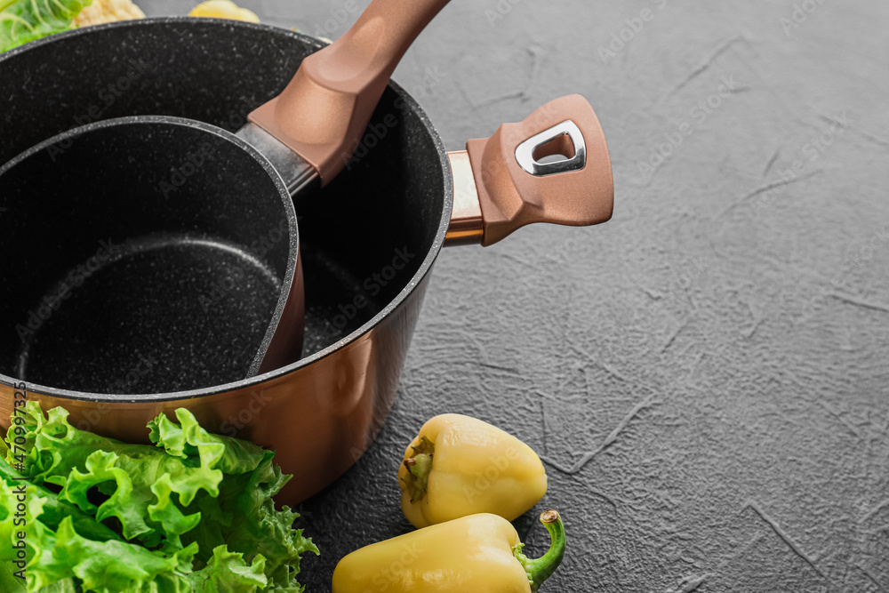 Cooking pot and saucepan with vegetables on dark background