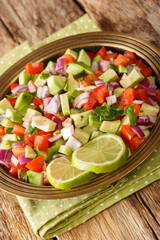 Wall Mural - Kachumbari Kenyan Fresh Tomato and Onion Salad close up in the plate on the table. Vertical