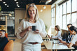 Leinwandbild Motiv Smiling mature businesswoman standing in a co-working space
