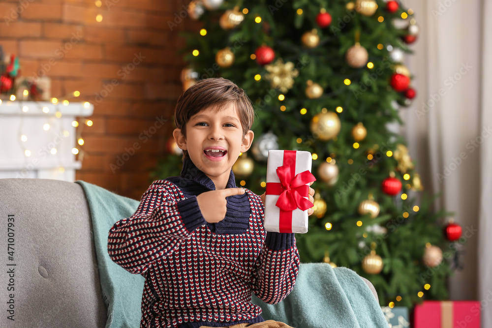Cute little boy with gift at home on Christmas eve