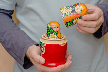 An adult male holding a wooden matryoshka doll. An uncovered tra