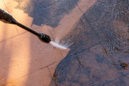 cleaning dirty backyard paving tiles with pressure washer cleaner.