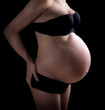 Belly of a pregnant woman over black background