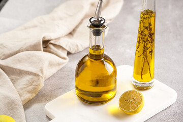 Two bottles with olive oil and fresh herbs - thyme - on white marble background