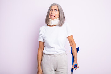 Wall Mural - senior pretty woman looking puzzled and confused. crutch and collar accident concept